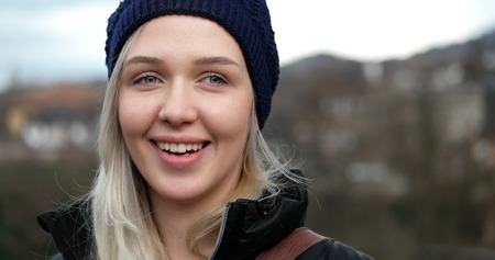 Outside portrait of beautiful blonde girl wearing beanie and coat. Nature background. Looking at cameraの写真素材