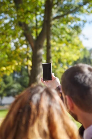 love, relationship, family and people concept - smiling couple hugging and taking selfie in autumn parkの写真素材