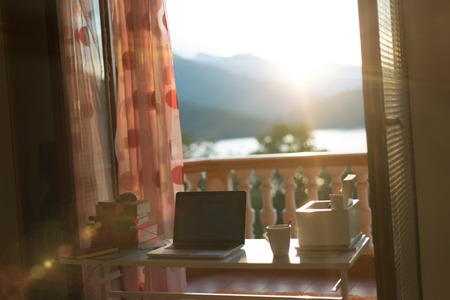 Morning sun shining on computer and coffee with dust in the airの写真素材
