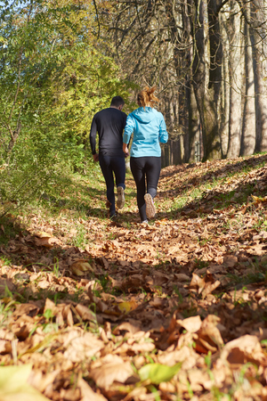 Young running couple jogging in autumn natureの写真素材