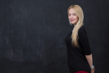 Portrait of attractive female teenager with long blond hair, black background and copy space.の写真素材