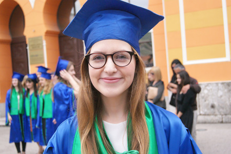 Graduate students wearing graduation hat and gown, outdoorsの写真素材