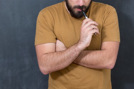 Man with concealed identity smoking a controversial vaping an electronic cigarette. Vaping is debatable in the health community if it is safe or a health riskの写真素材