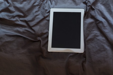 White tablet on the bed on a bed - mockupの写真素材
