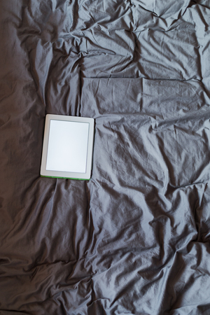 White tablet on the bed on a bed - mockupの写真素材