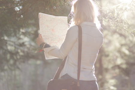 traveler girl searching right direction on map, bright orange sunset light, traveling along Europe, freedom and active lifestyle conceptの写真素材