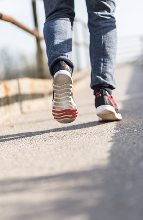 Running sport. Man runner legs and shoes in action on road outdoors at sunset. Male athlete model.の写真素材