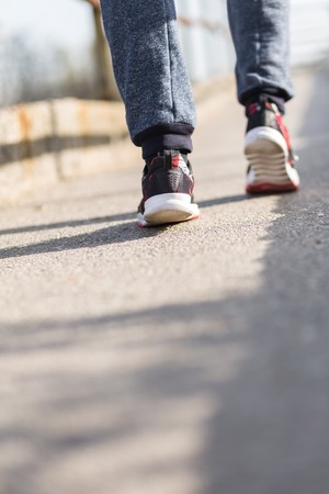 Running sport. Man runner legs and shoes in action on road outdoors at sunset. Male athlete model.の写真素材