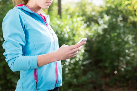 Running woman. Female runner relaxing after jogging outdoor workout. Beautiful fit girl using her mobile phone.の写真素材