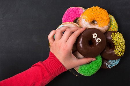 people, food, junk-food and eating concept - close up of female hand holding glazed donutの写真素材