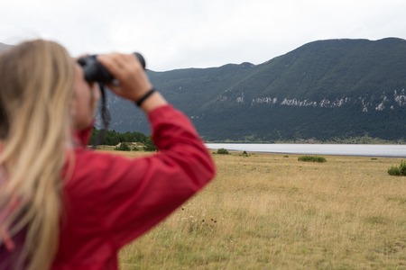 young blonde woman hiking and watching through binoculars.の写真素材