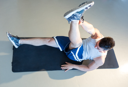 Male fitness model doing sit ups and crunches exercising abdominal musclesの写真素材