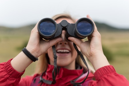young blonde woman hiking and watching through binoculars.の写真素材