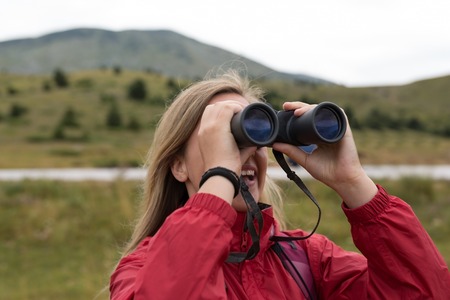 young blonde woman hiking and watching through binoculars.の写真素材