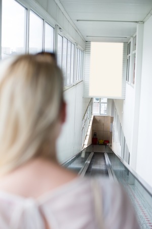 Cheerful Pretty Young Lady Taking the Escalator Ride and shoppingの写真素材