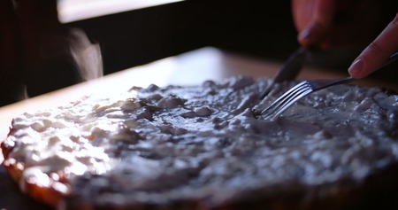 Cutting the pie with sour cream over it while food is still smokingの写真素材