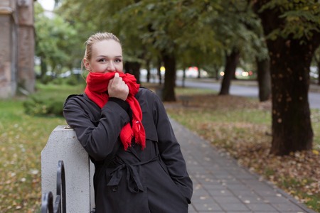 Happy blond fashion woman in classic coat walking outdoorの写真素材