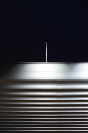 Blank billboard with lights on the top of brick wall at night city background, mock upの写真素材