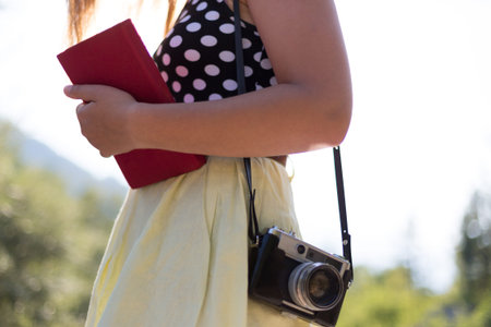young woman sitting on rock in nature with vintage cameraの写真素材