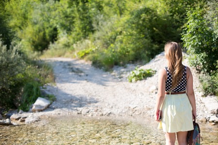 Young woman hiker with bag enjoying on a stream in natureの写真素材