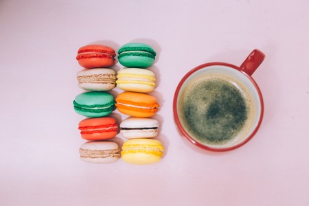 A cup of morning americano coffee with colorfull french macarons on a  pink backgroundの写真素材