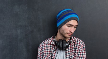 Handsome DJ posing in studio on dark background with headphones around neckの写真素材