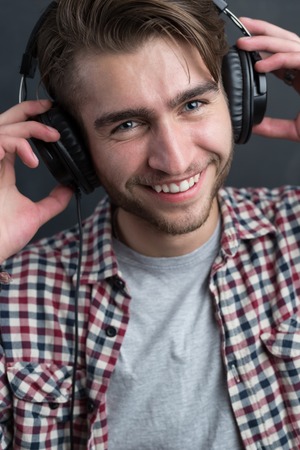 Portrait of confident young DJ with stylish haircut and headphones  on dark background.の写真素材