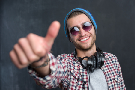 Carefree music lover. Joyful young man in headphones smiling against chalkboard backgroundの写真素材