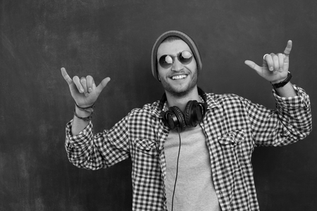 Handsome DJ posing in studio on dark background with headphones around neckの写真素材