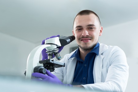 young doctor scientist in bright labaratory work research and analyse content of test tubes representing chemistry and research conceptの写真素材