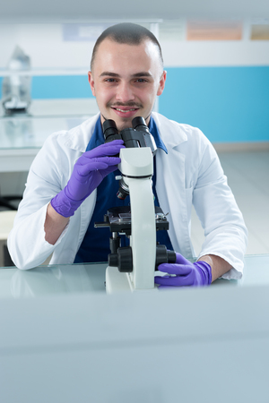 Young scientist investigating microbiological substance in microscopeの写真素材