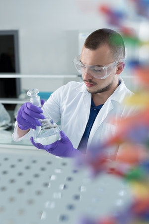 young doctor scientist in bright labaratory work research and analyse content of test tubes representing chemistry and research conceptの写真素材