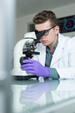 Scientist looking through a microscope in a laboratoryの写真素材