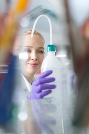 Woman researcher is surrounded by medical vials and flasksの写真素材