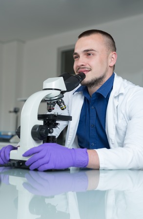 young doctor scientist in bright labaratory work research and analyse content of test tubes representing chemistry and research conceptの写真素材