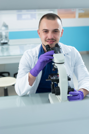 young doctor scientist in bright labaratory work research and analyse content of test tubes representing chemistry and research conceptの写真素材