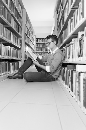 young student reading book between the shelves in the libraryの写真素材