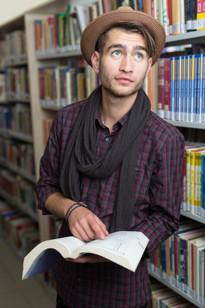 young student reading book between the shelves in the libraryの写真素材