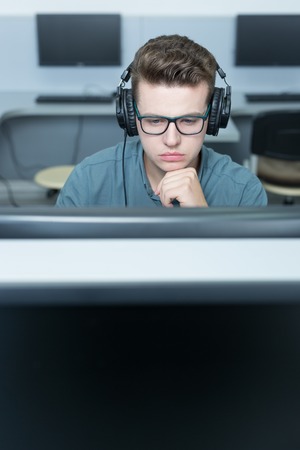Young software engineer working in office with headphones on his headの写真素材