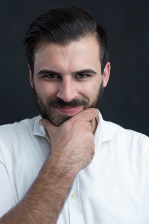 Portrait of a  young bearded man smiling against black chalkboardの写真素材