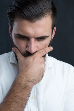 Portrait of a  young bearded man thinking against black chalkboardの写真素材