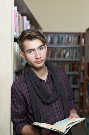 young student reading book between the shelves in the libraryの写真素材
