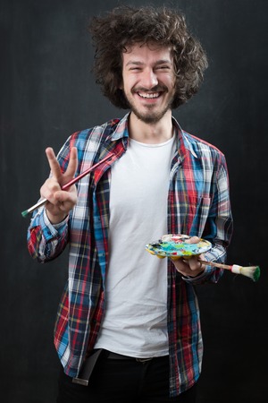 Portrait of an artist holding his brushe and paints. Shot in a studio.の写真素材