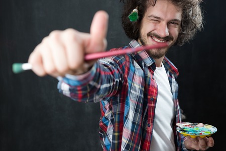 Portrait of an artist holding his brushe and paints. Shot in a studio.の写真素材