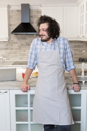 Good looking man in an apron in fron of kitchen at homeのeditorial素材
