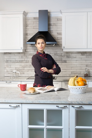 Gorgeous woman drinking coffe and reading magazine in her kitchenのeditorial素材