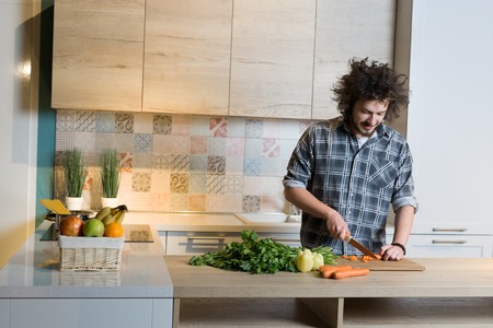 Handsome man cooking at home preparing salad in kitchen.の写真素材