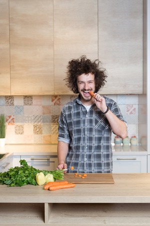 Handsome man cooking vegetable salad in kitchenの写真素材