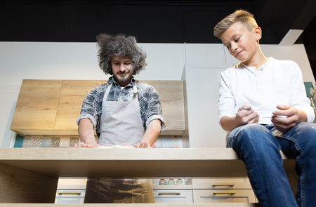 Father and son pre[aring pizza in kitchen. Relationship father and sonの写真素材