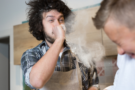 a father and his son preparing a cake in the kitchen. Father and son having flour fight in kitchenの写真素材